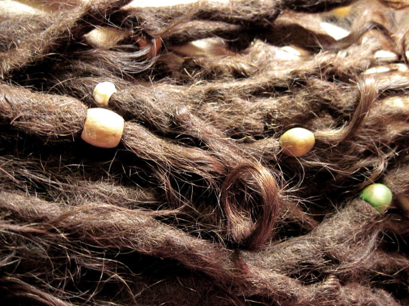 Bronzeröllchen und Schmuck in Dreadlocks